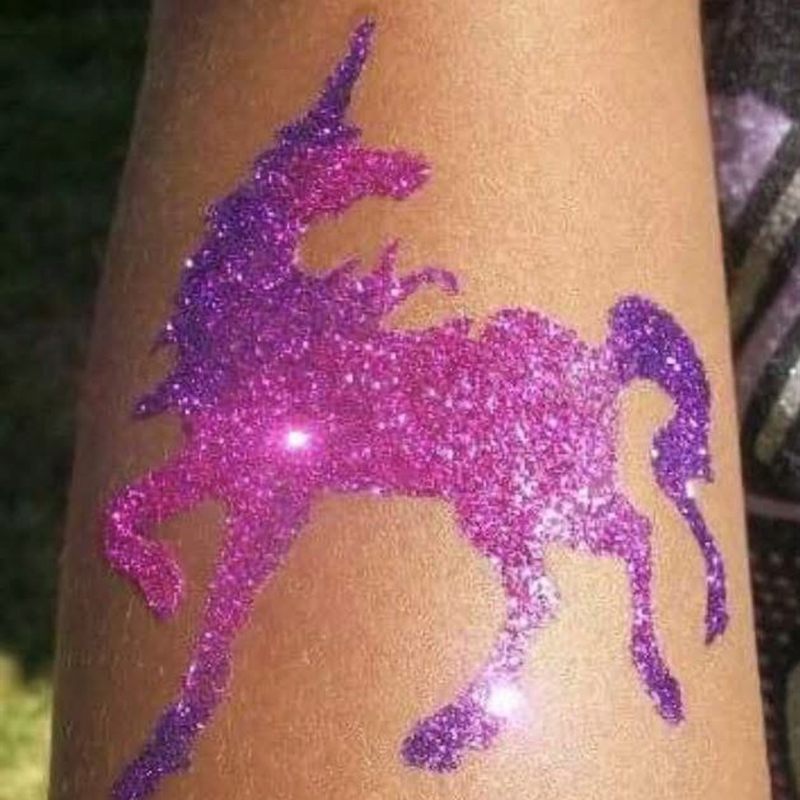 Purple glitter unicorn tattoo on an arm